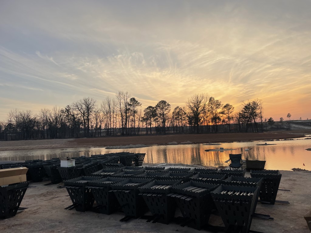 Sun setting behind fish habitats next to lake